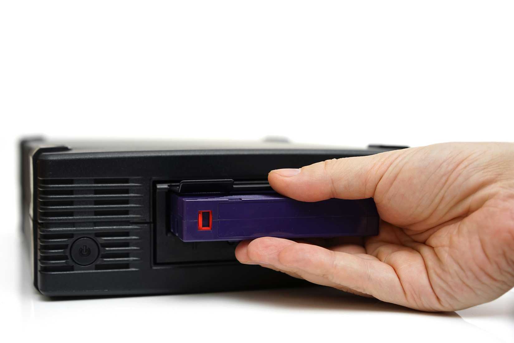 A person inserts a tape into an LTO drive.
