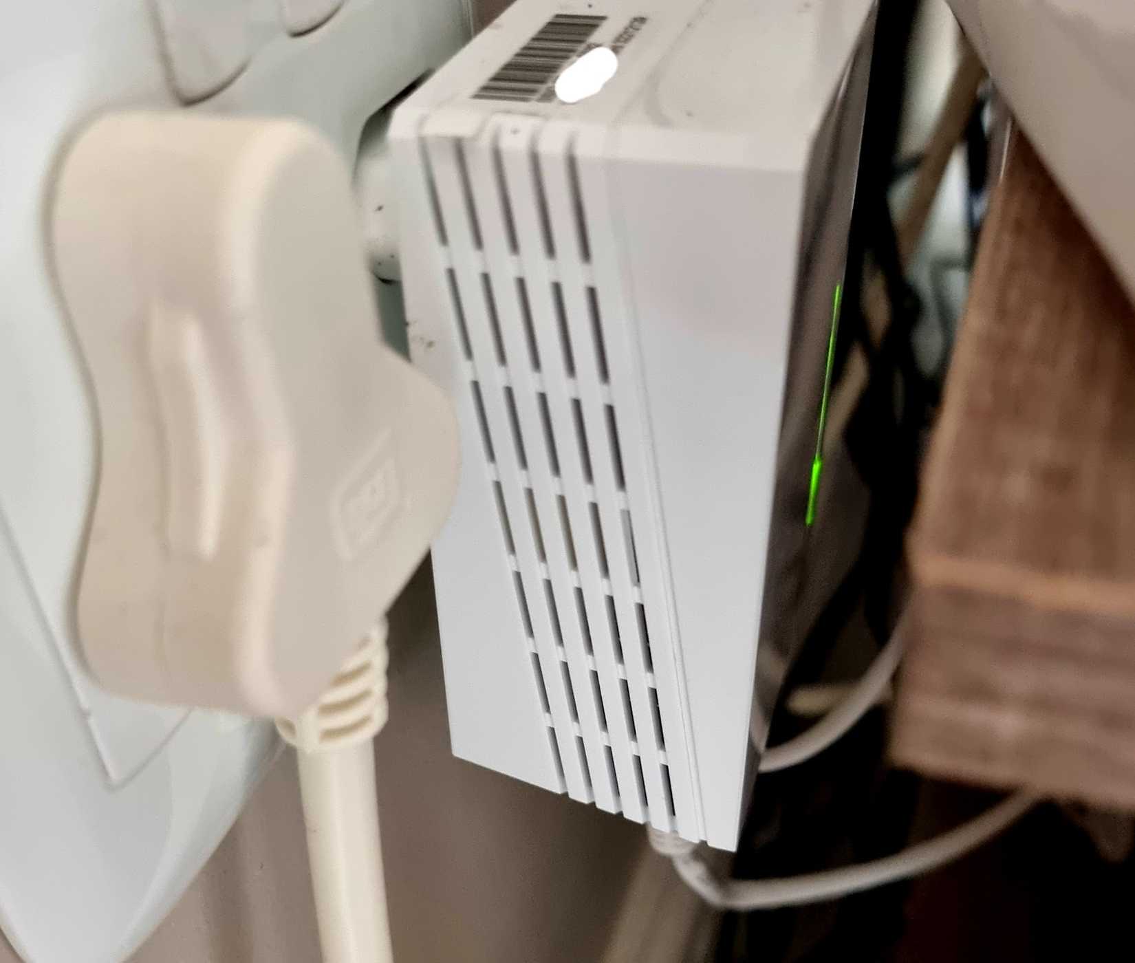 Close-up of a powerline networking adapter plugged into a wall outlet beside another connected power plug.