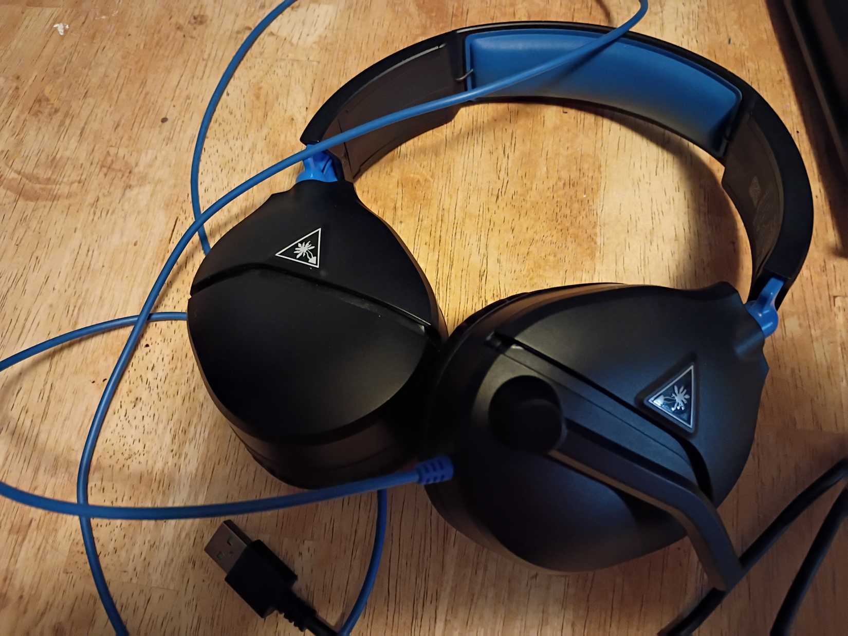 Blue Turtle Beach headphones sitting on a table.