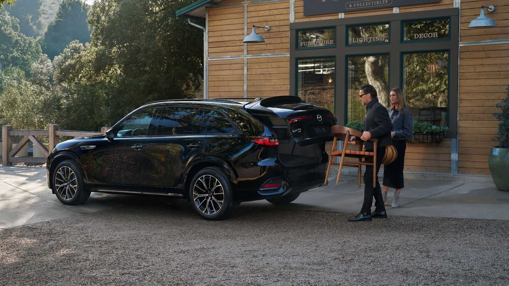 Shot of a man and woman loading items into the back of a black 2026 Mazda CX-70.