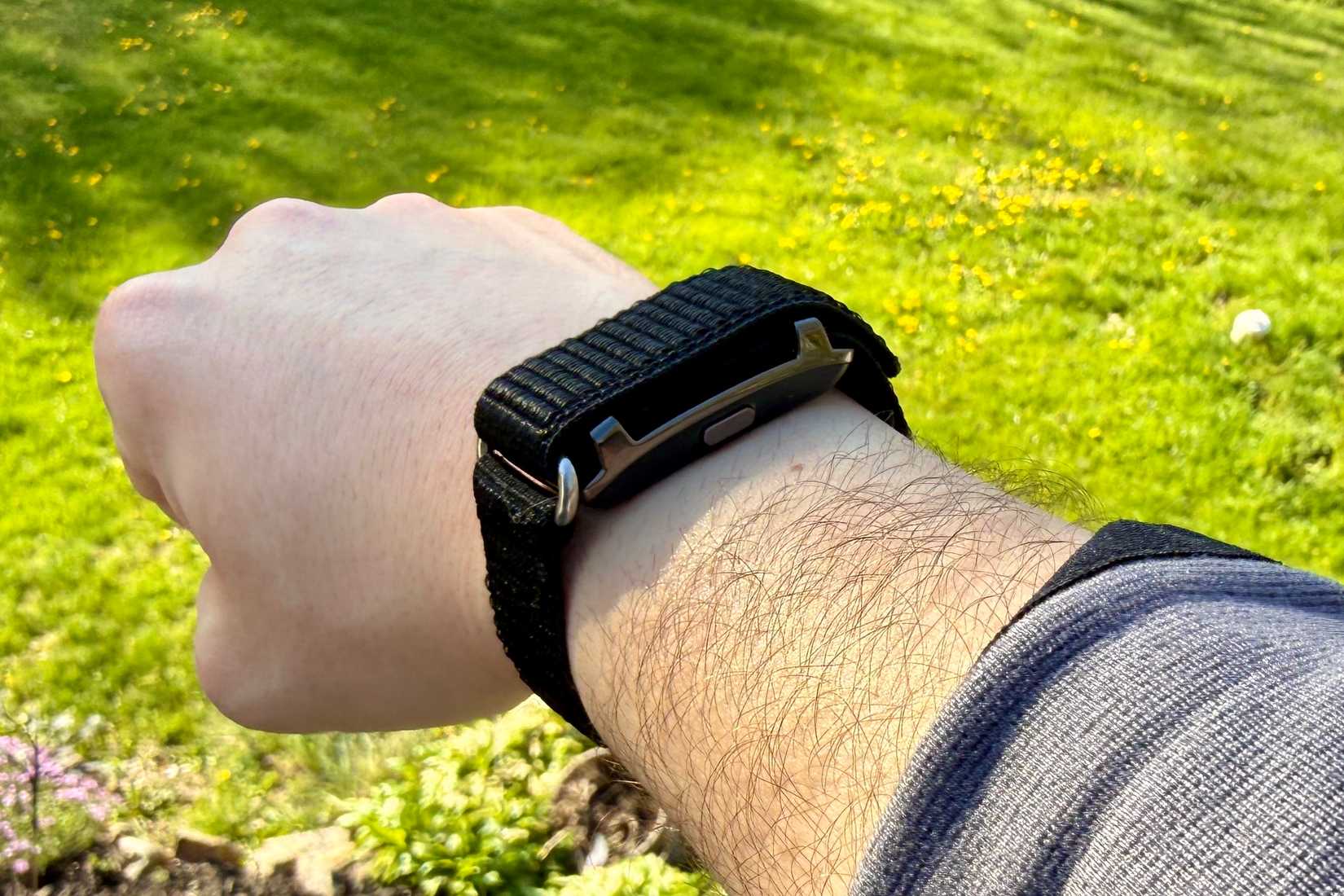 Qiunhang Smart Bracelet Fitness Tracker worn in front of the grass.