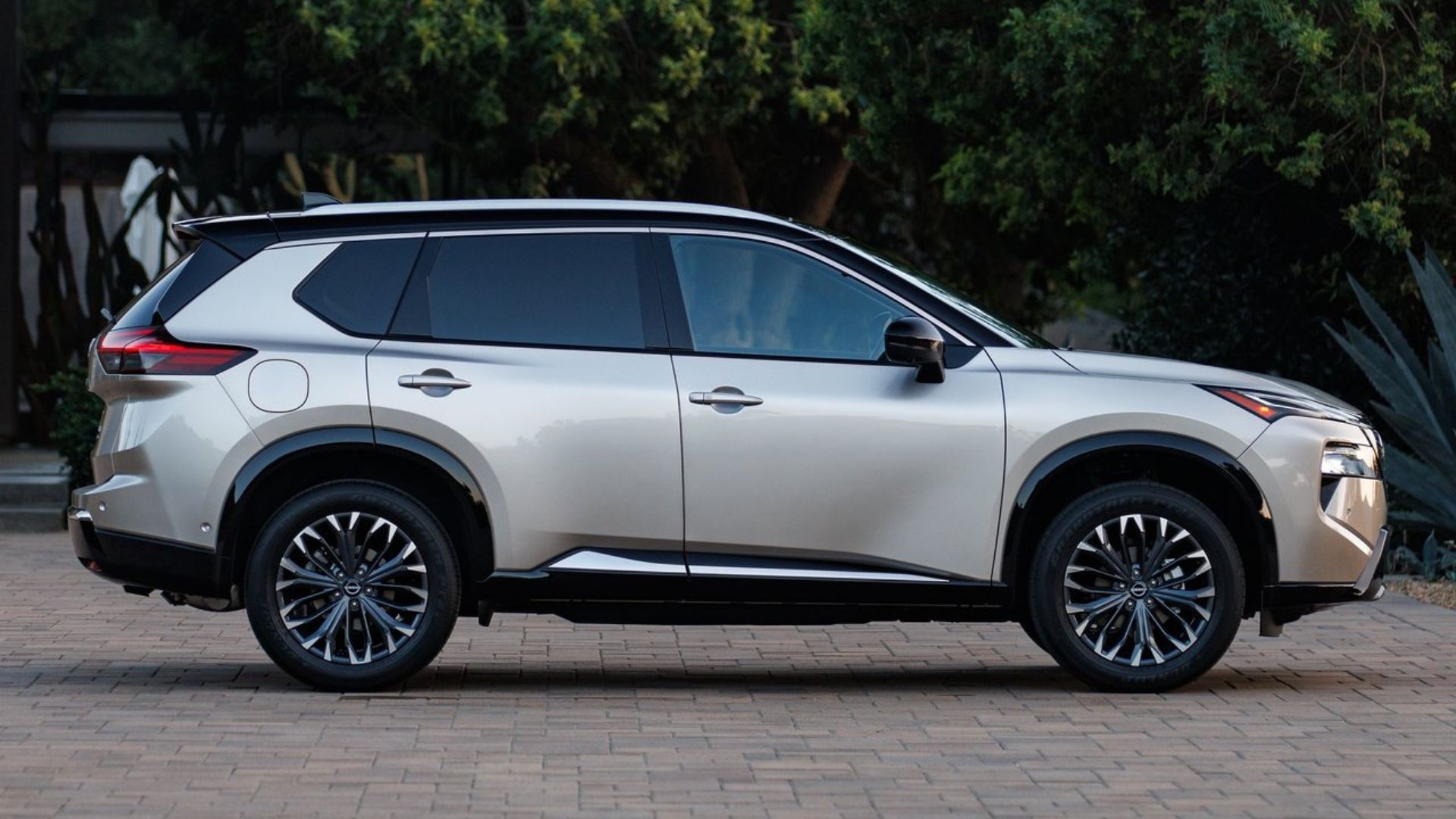 Static side profile shot of a gold 2024 Nissan Rogue.