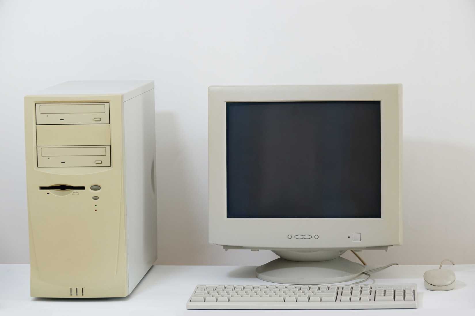Beige desktop PC with dual floppy drives and a CRT monitor on a white desk.