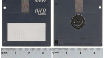 A Sony HiFD disk lying flat on a table with a measuring tape placed under it.