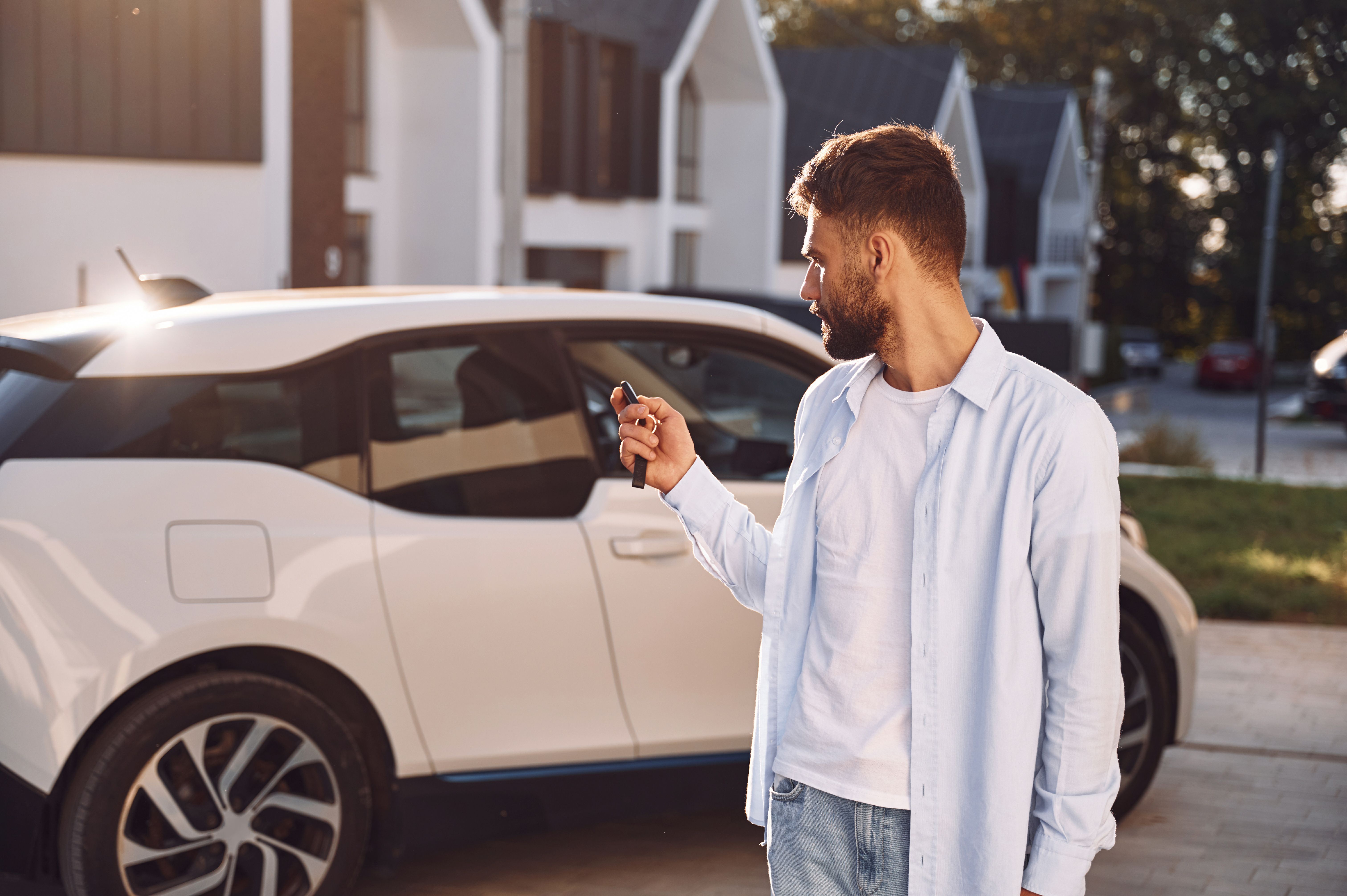 Young man locking a car in the driveway