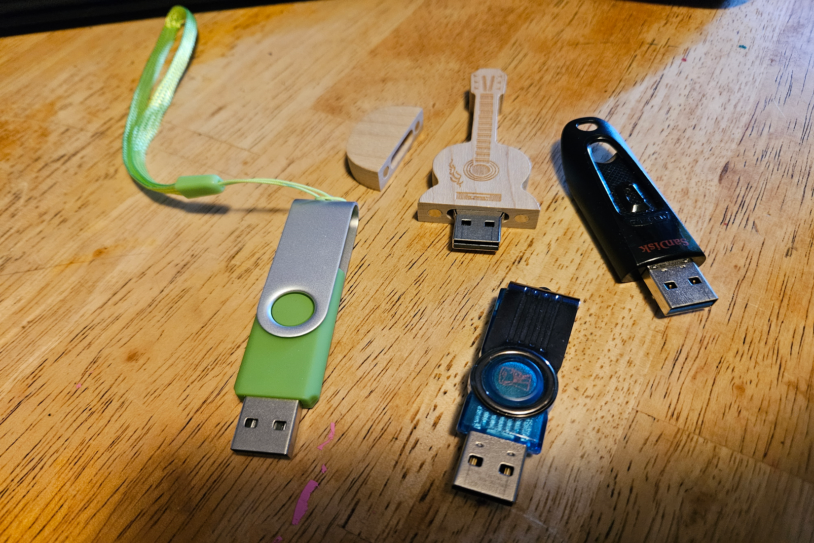 A green, blue, black, and guitar-shaped USB drive sit together on a table.