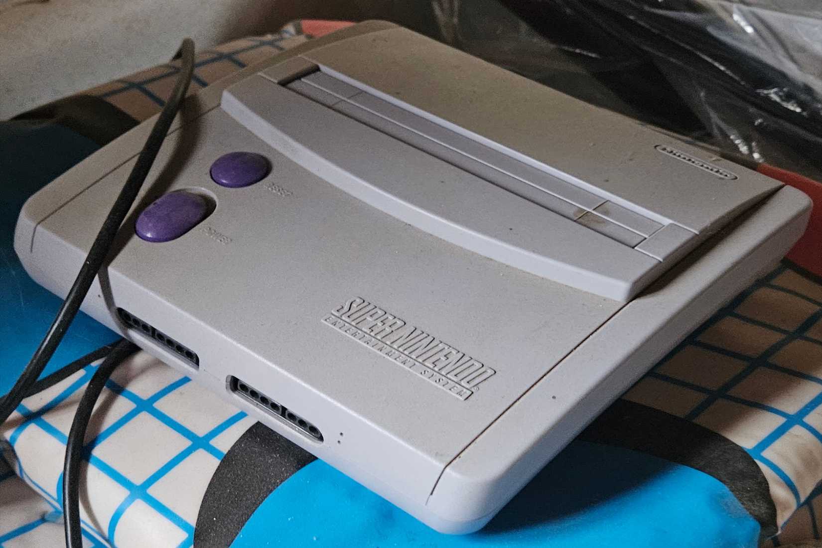 A super nintendo console on top of a multi-colored pad.
