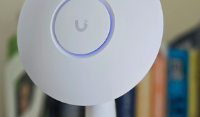 A UniFi access point mounted to a 3D printed stand with books in the background.