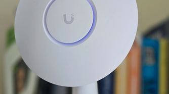 A UniFi access point mounted to a 3D printed stand with books in the background.