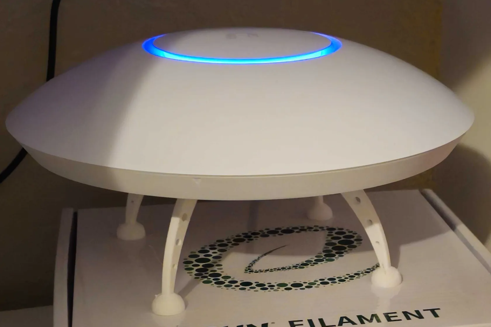 A UniFi network access point sitting on top of 3D printed UFO feet.