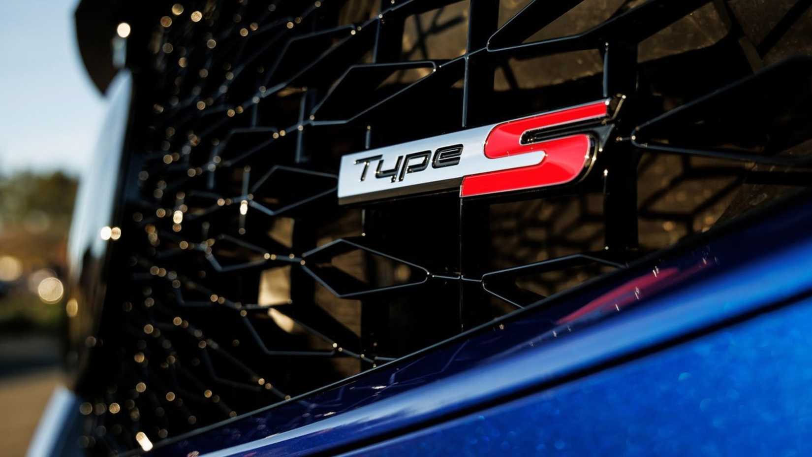A close-up of the Type S badge on the front grille of the blue 2022 Acura MDX Type S.