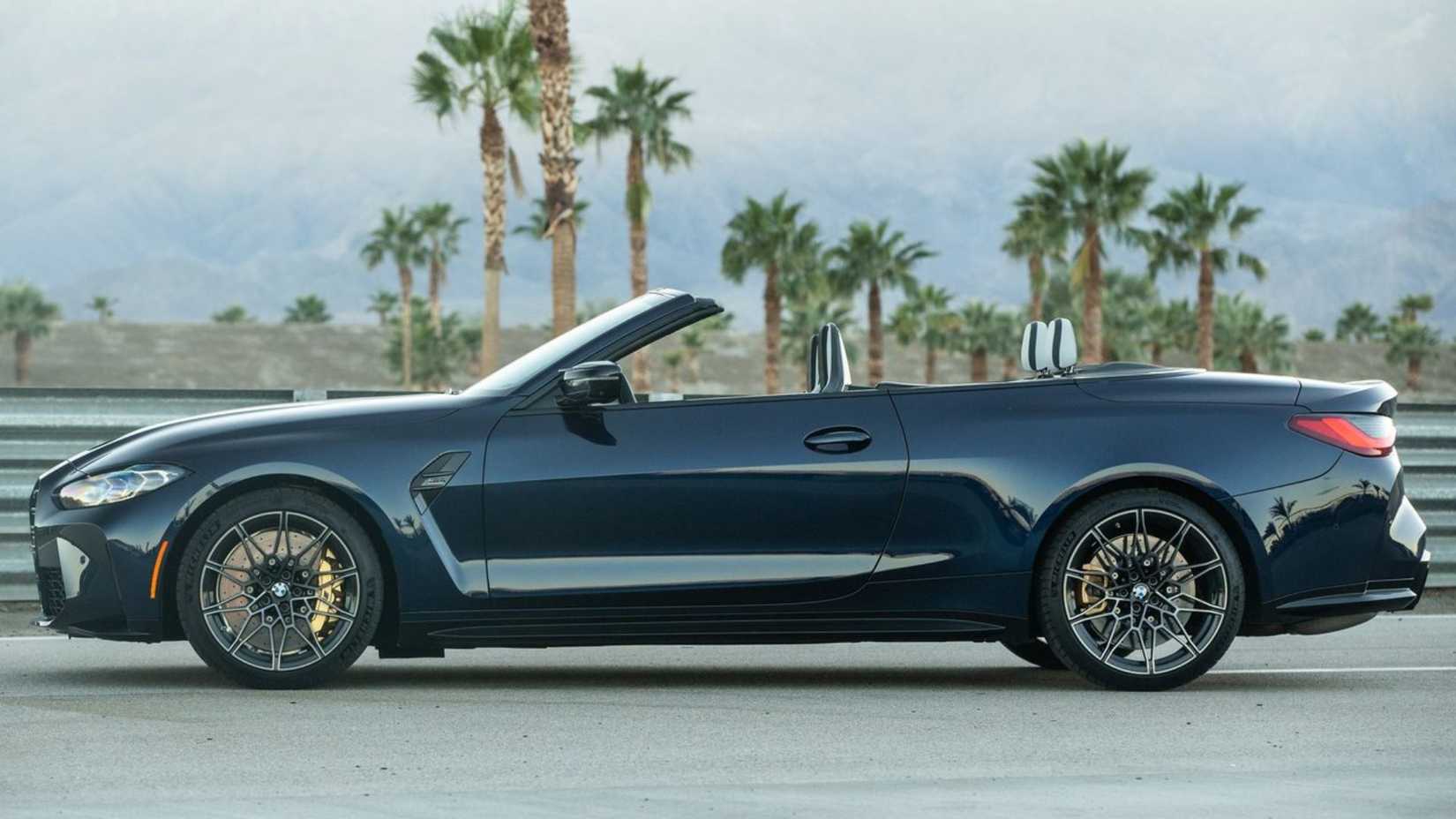 Static side profile shot of a black 2022 BMW M4 Competition Convertible xDrive.