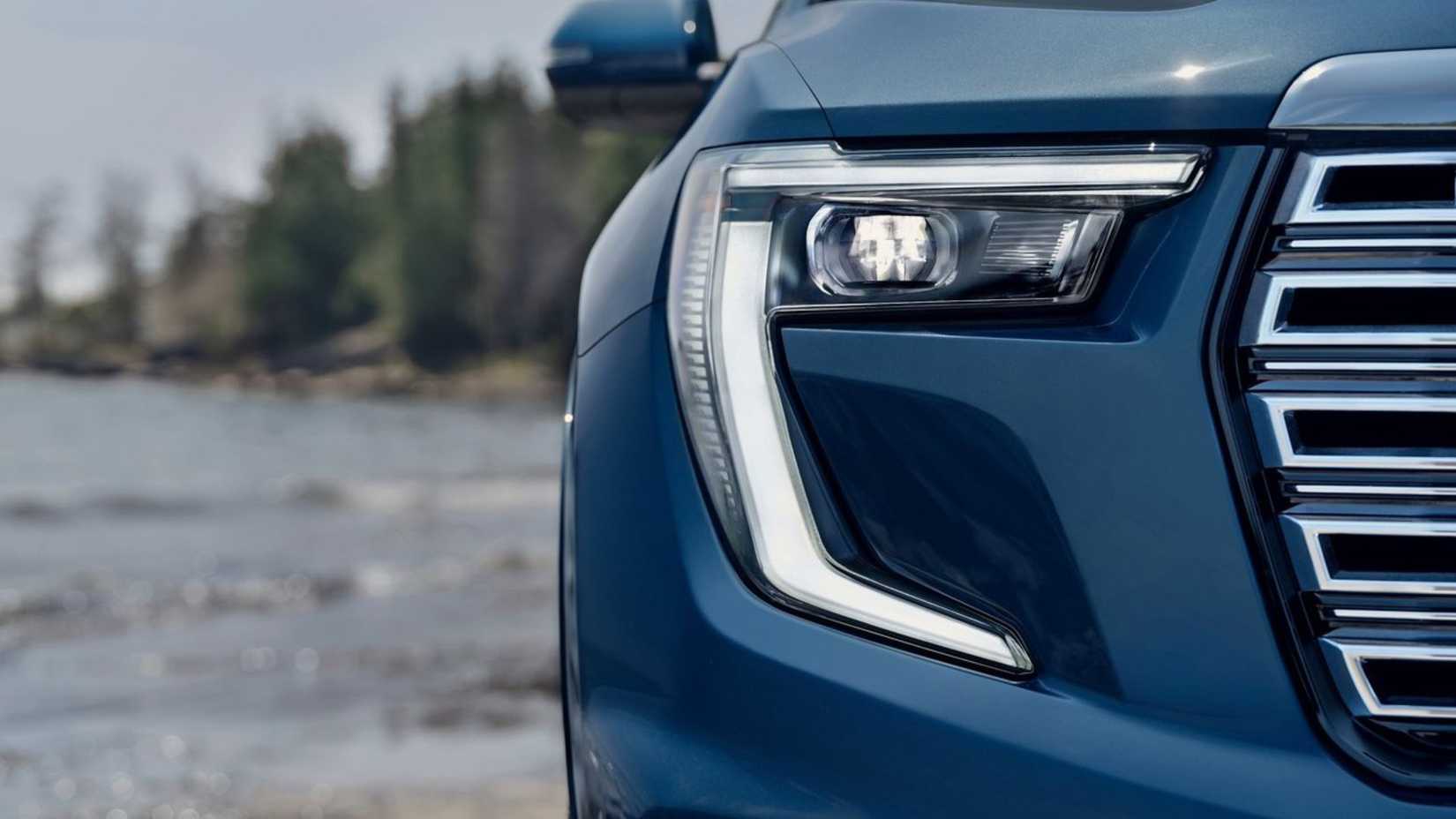 Close-up shot of the headlight on a blue 2024 GMC Acadia.