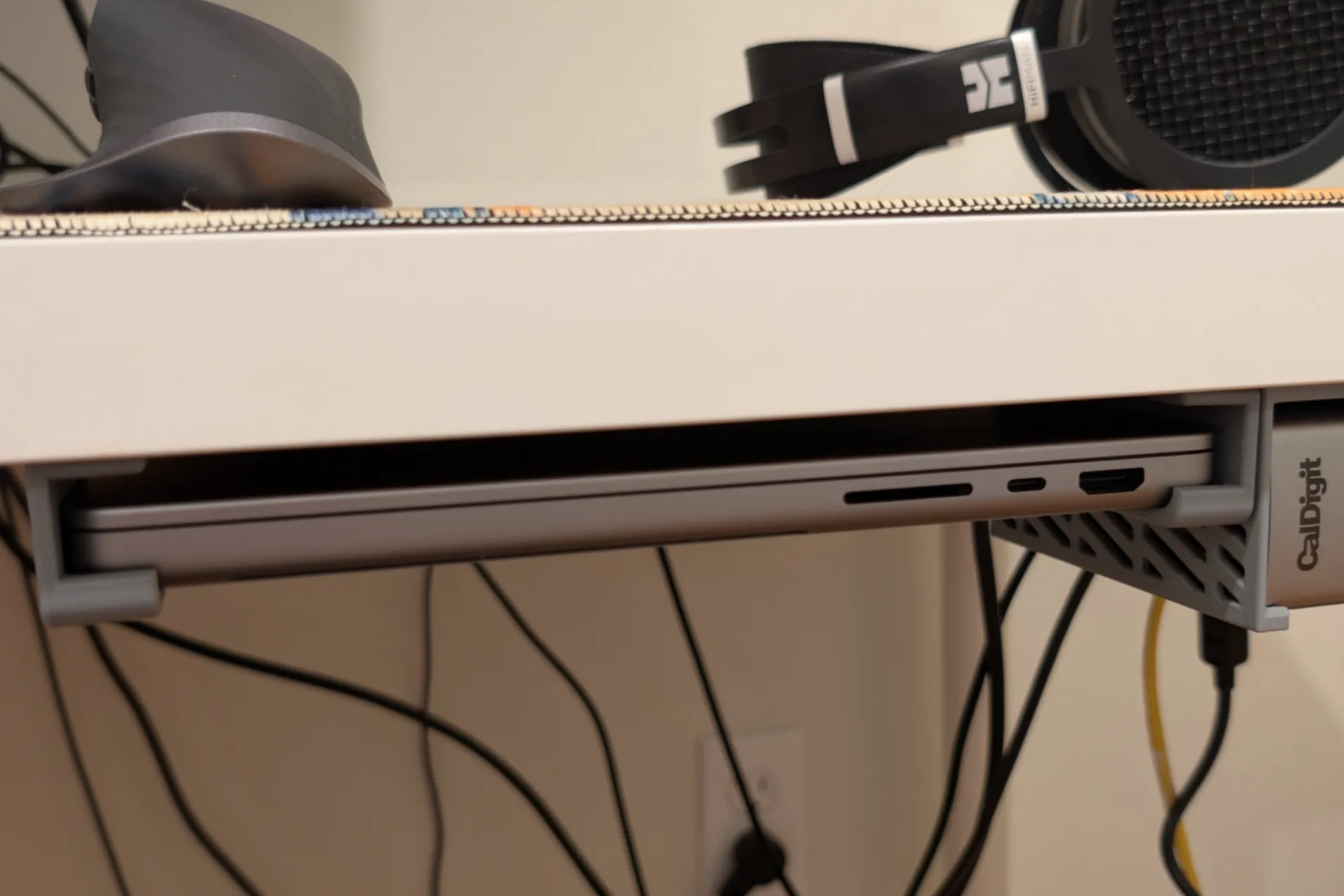 MacBook Pro mounted under a desk with a 3D printed mount.
