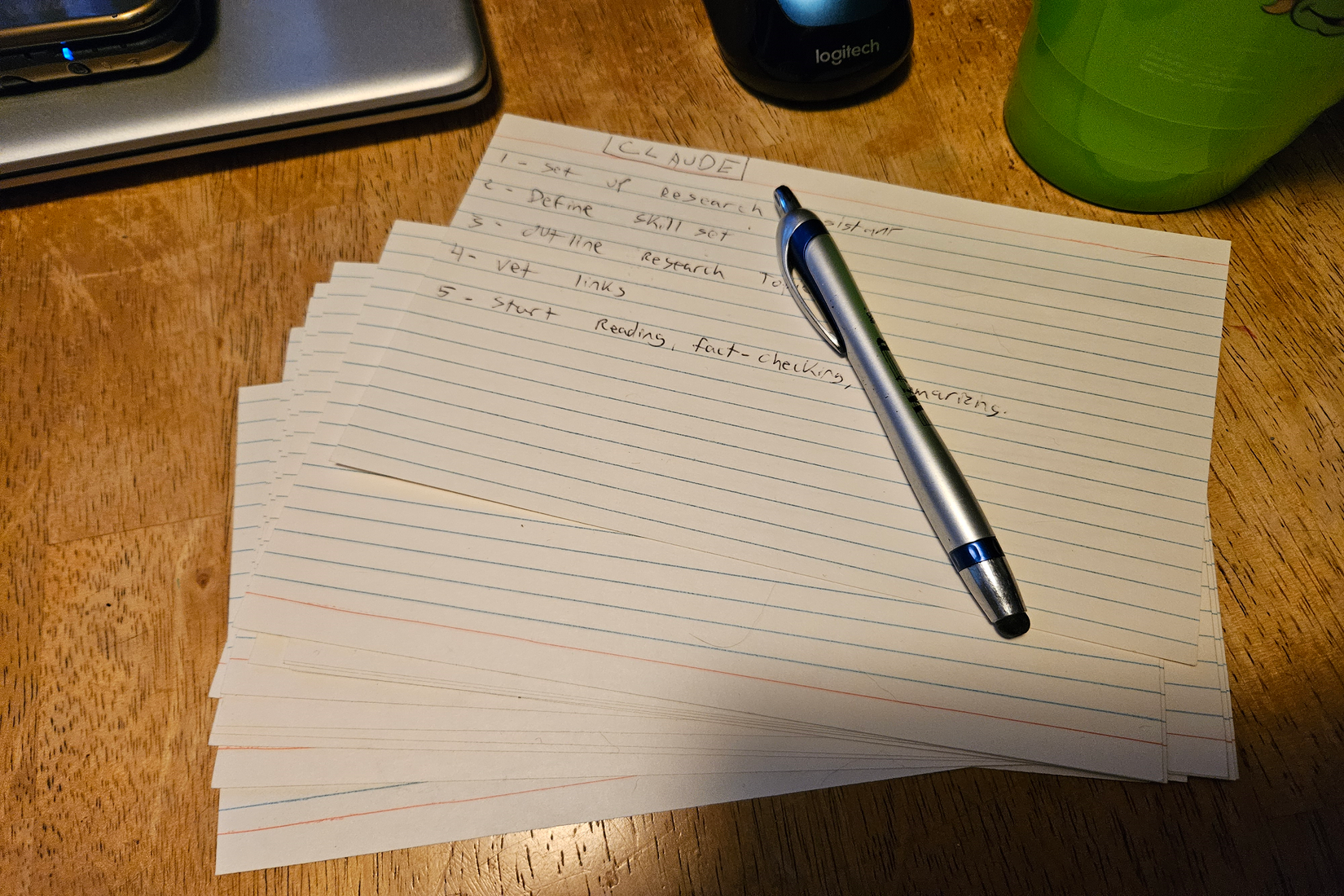 Notcards and a pen sitting on a table near a closed laptop.