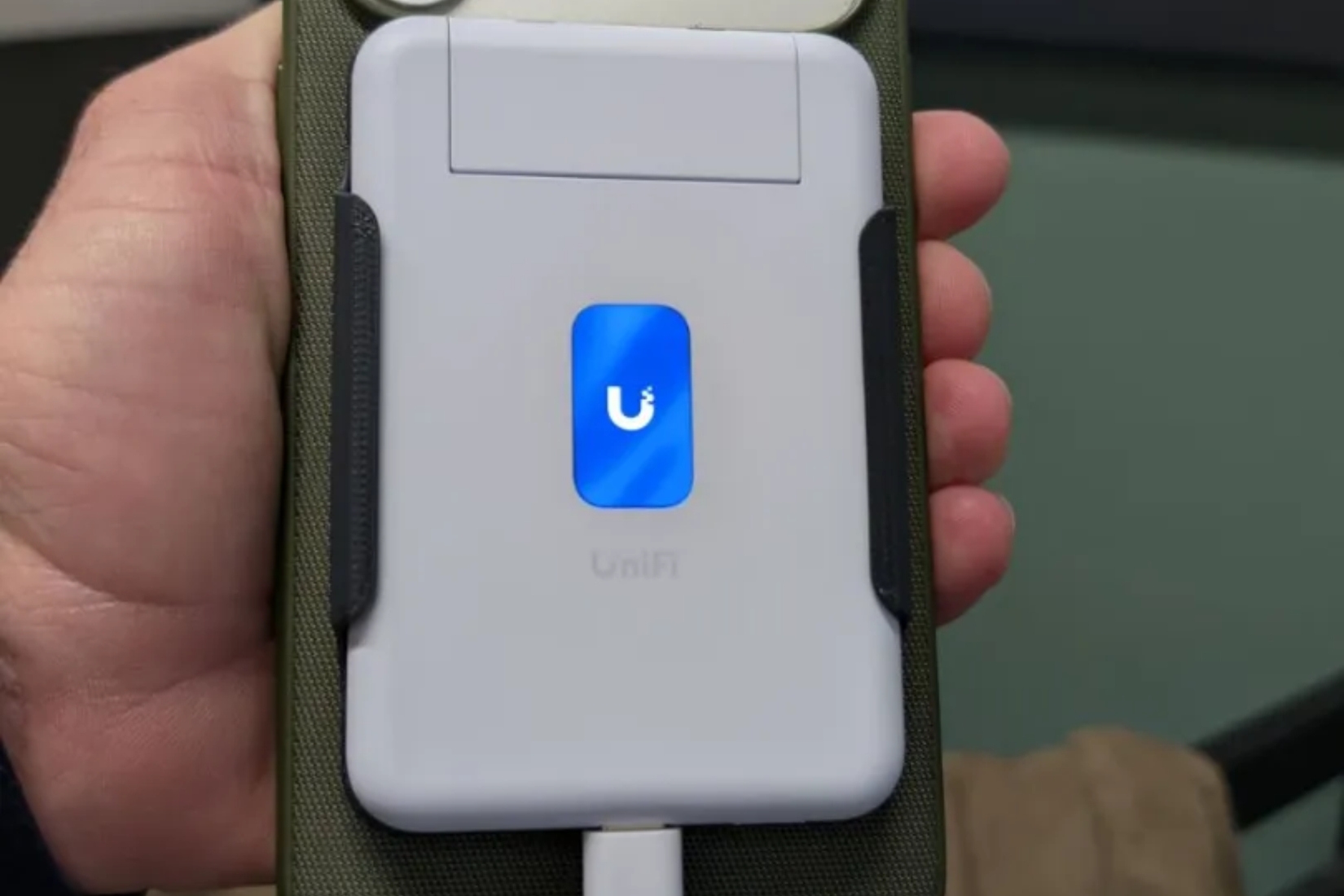 The UniFi Travel Router mounted to the back of an iPhone 17 Pro with a MagSafe case.