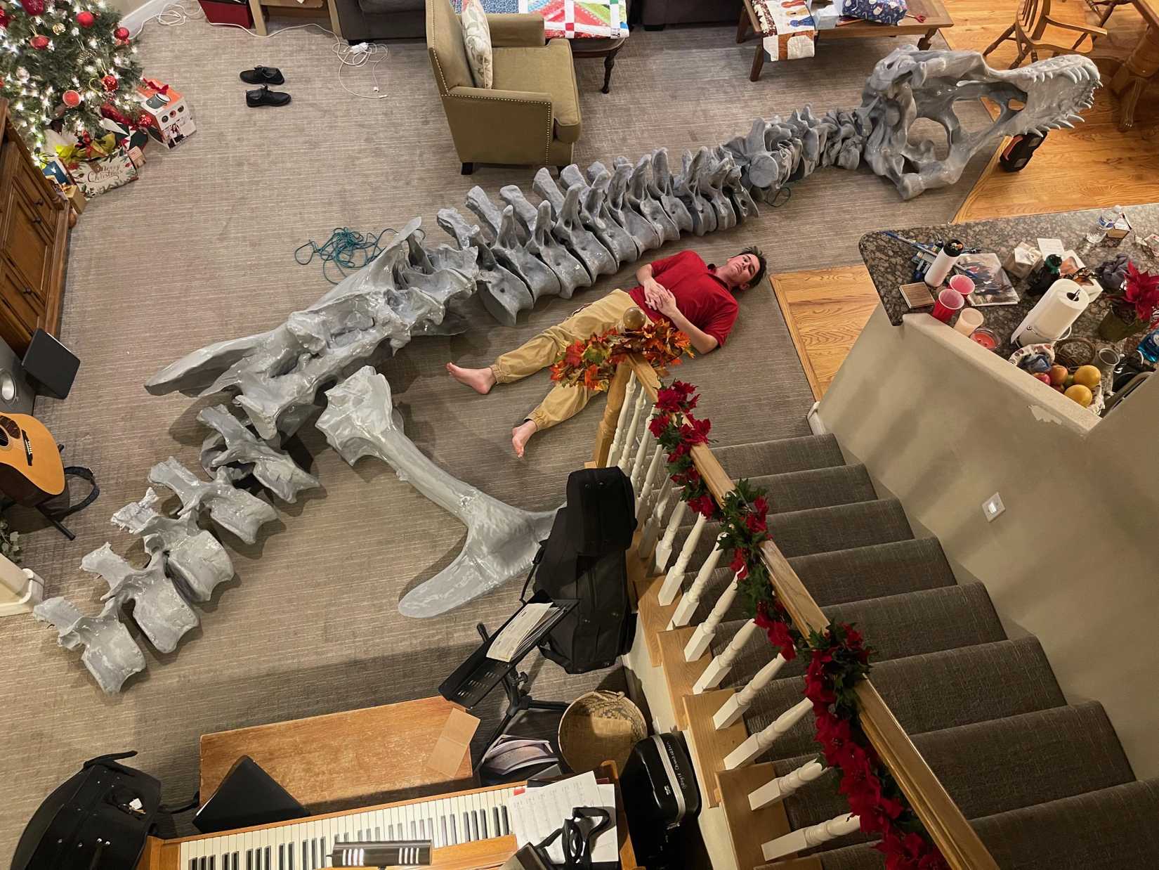 Life-sized dinosaur skeleton laid out beside its maker for scale.