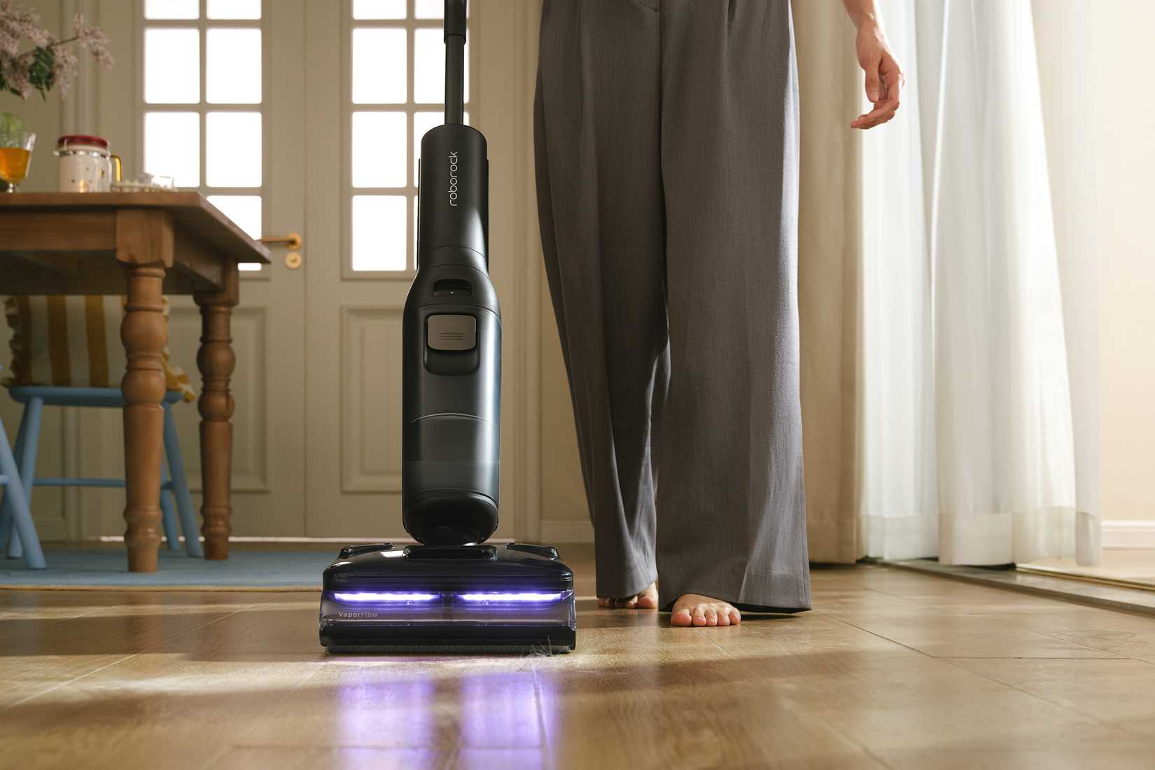 The person pushing the Roborock F25 Steam across the dusty dining room floor