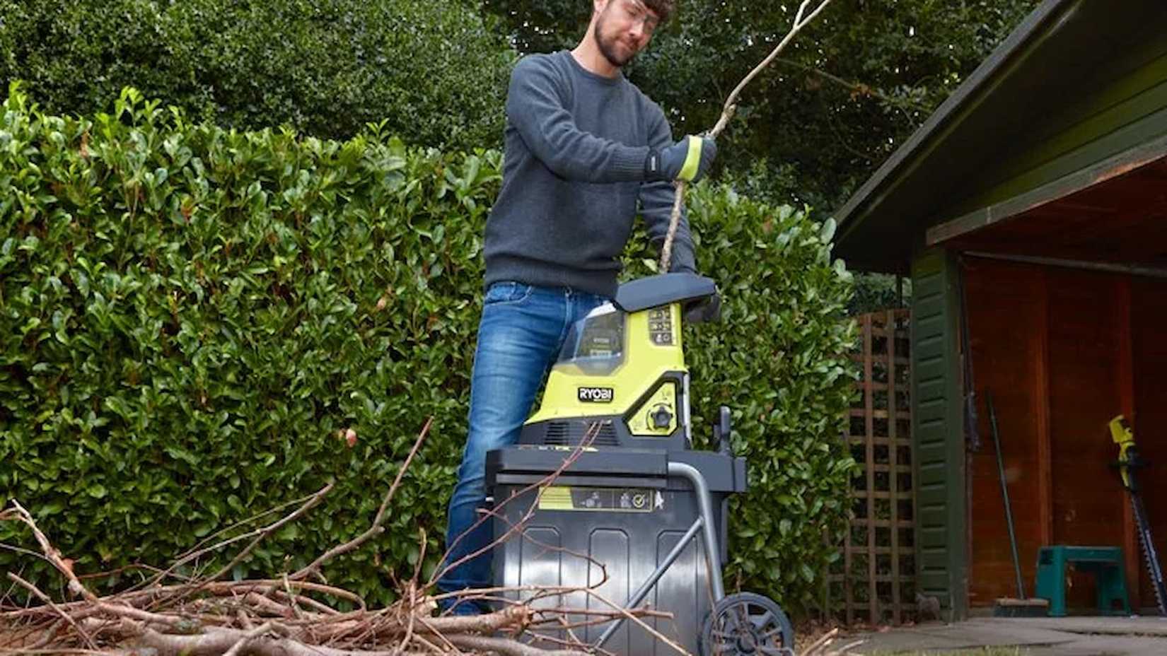 36V MAX POWER Cordless Brushless Shredder being used to shred branches next to a garage near a home.