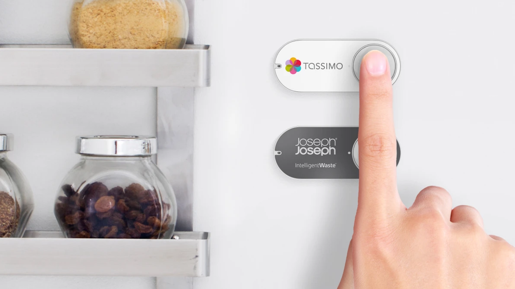 A finger pressing an Amazon Dash button on the wall of a kitchen.