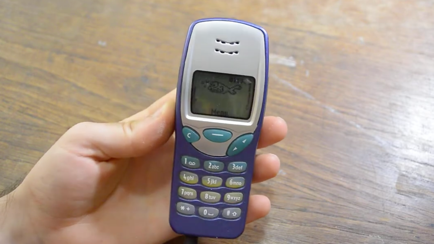 A Nokia 3210 held in a person's hand.