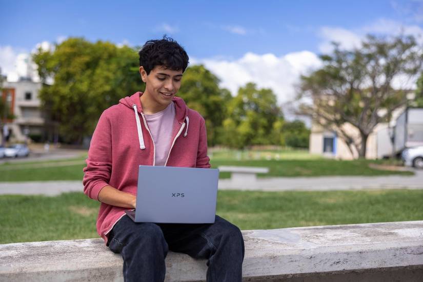 Man using the Dell XPS 13 while sitting on a wall