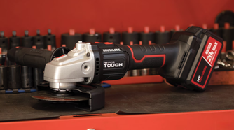 The Hyper Tough cordless angle grinder sitting on a workbench with sockets behind it.