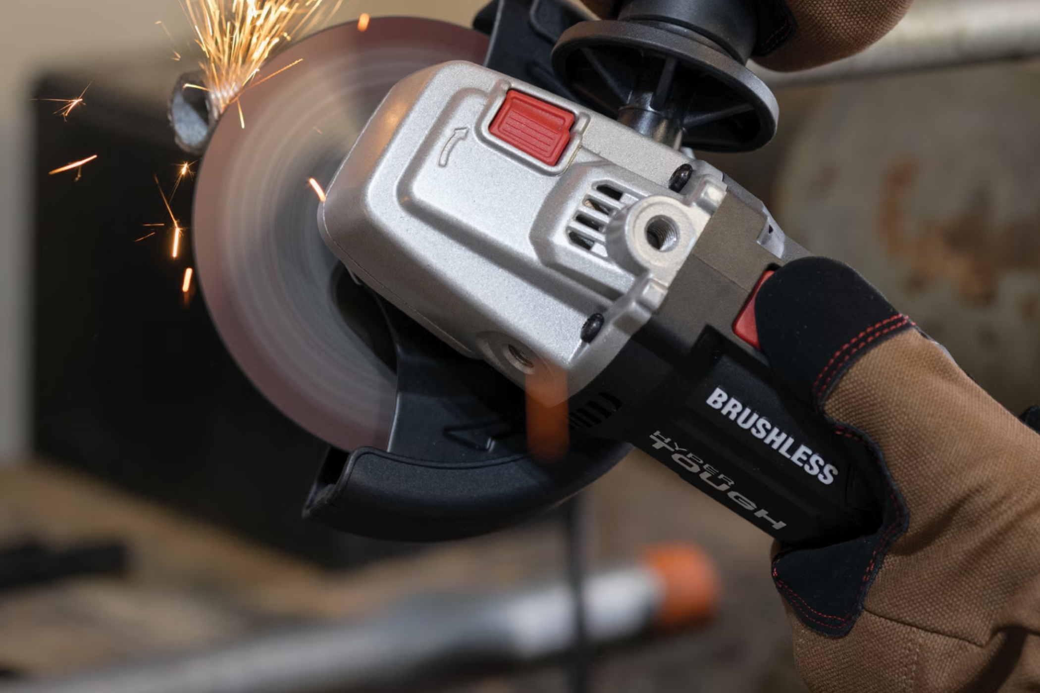 A person using the Hyper Tough angle grinder to cut a pipe.