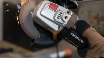 A person using the Hyper Tough angle grinder to cut a pipe.