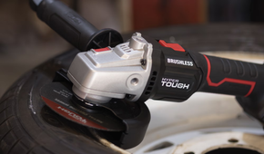 The cordless Hyper Tough angle grinder sitting on a tire.