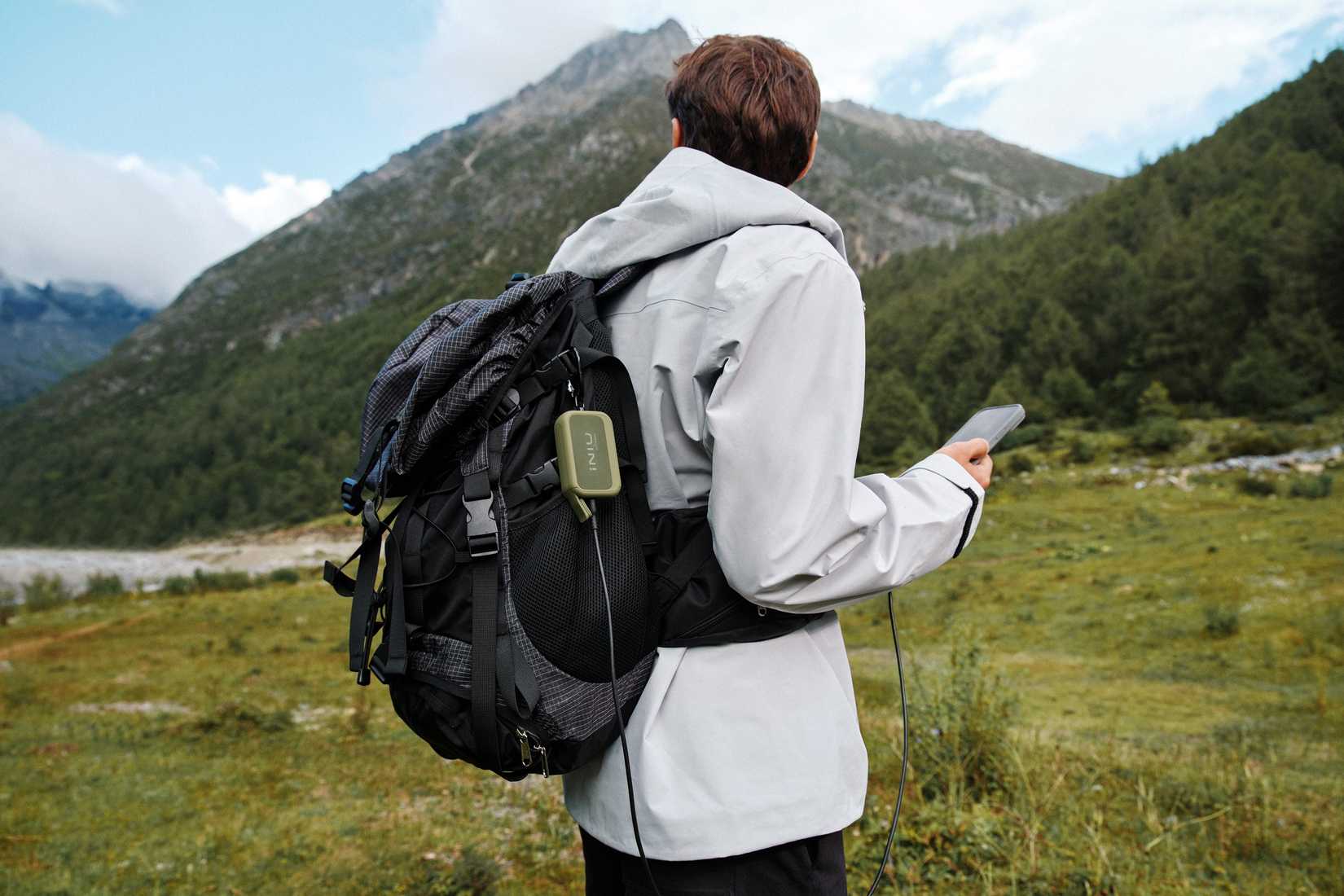 INIU Rugged Series power bank attached to a man's backpack while he's charging his phone.