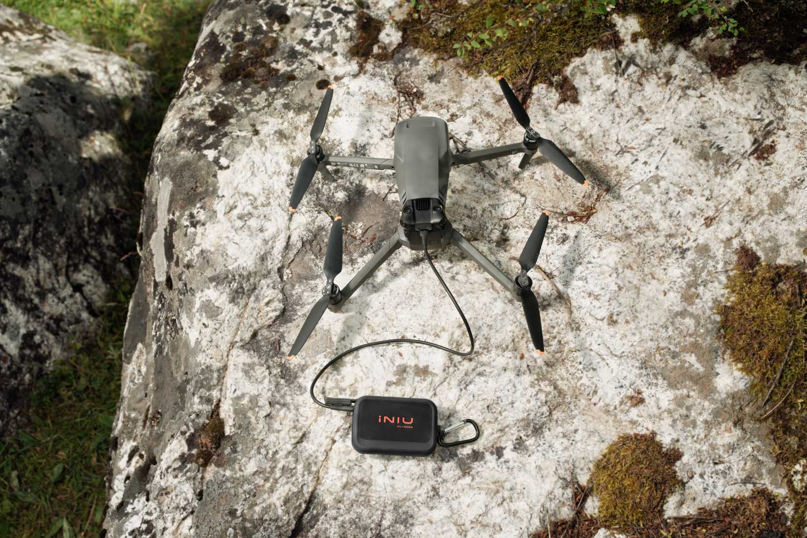 INIU Rugged Series power bank charging a drone on a rock.