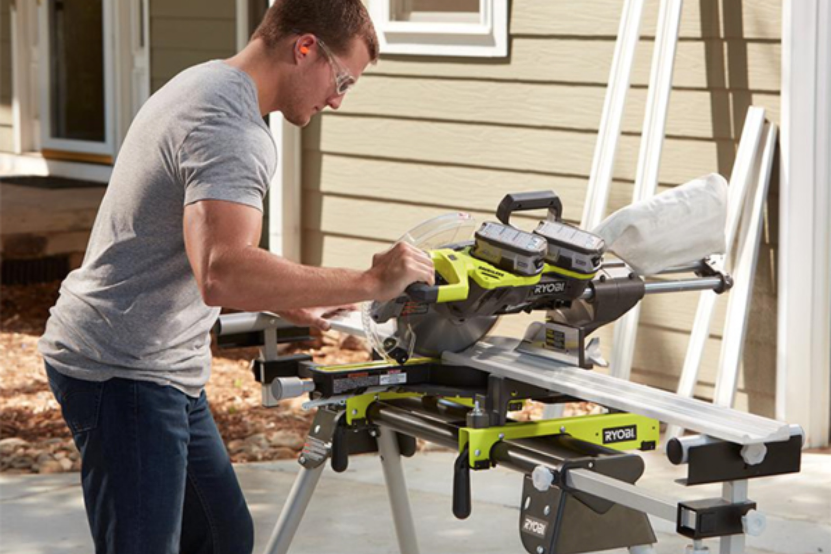 5 редких инструментов Ryobi, ставших коллекционными редкостями Человек разрезает обшивку на улице с помощью торцовочной пилы Ryobi, питающейся от двух аккумуляторов.