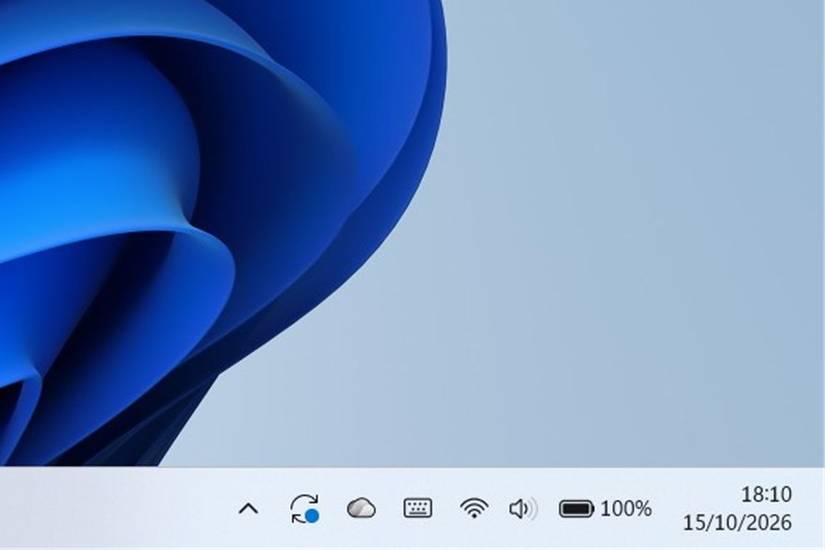 Windows 11 taskbar showing the system tray with a battery icon unplugged at 100 percent status.
