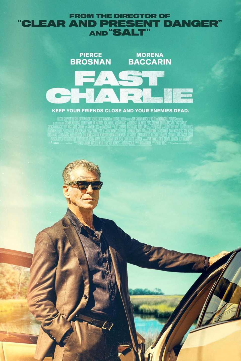 Fast Charlie Movie Poster - man standing against teal sky backdrop, hand on car looking outward