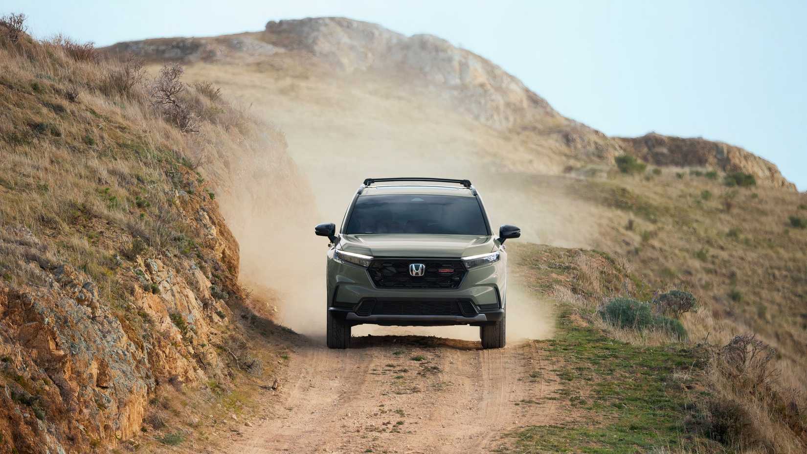 Dynamic front-end shot of a 2026 Honda CR-V Hybrid TrailSport drivingh off-road.