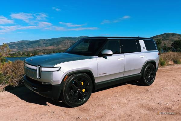 Rivian R1S in silver parked on dirt in front of a lake