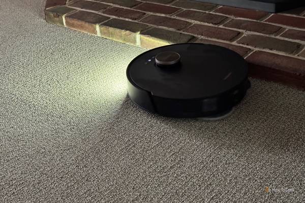 Showing a DreameBot L20 Ultra robot vacuum cleaning with its front light on.