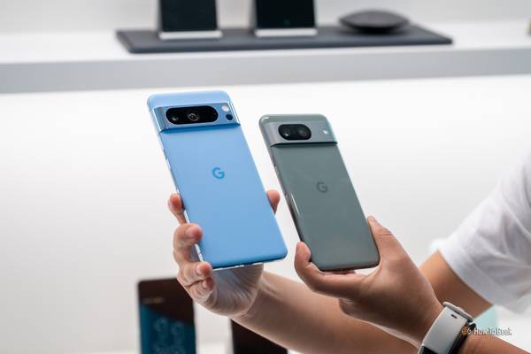 Person holding up the Google Pixel 8 and Google Pixel 8 Pro side by side