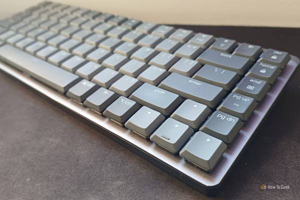 Logitech MX Mechanical Mini keyboard viewed from an angle, with the directional keys on the foreground, over a black, rubbery desk mat