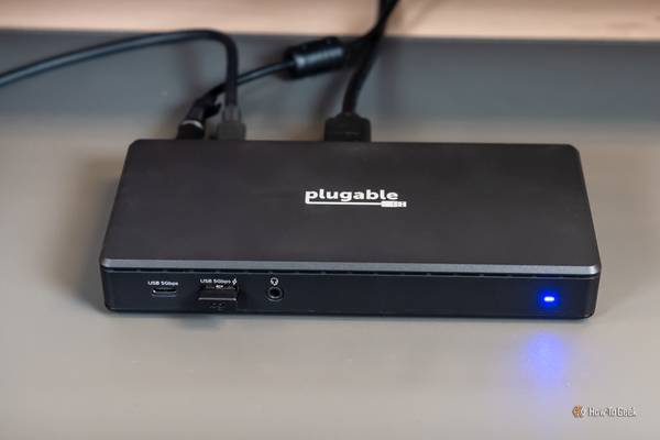 The Plugable USB C Dual HDMI Docking Station with cables plugged in and the light on