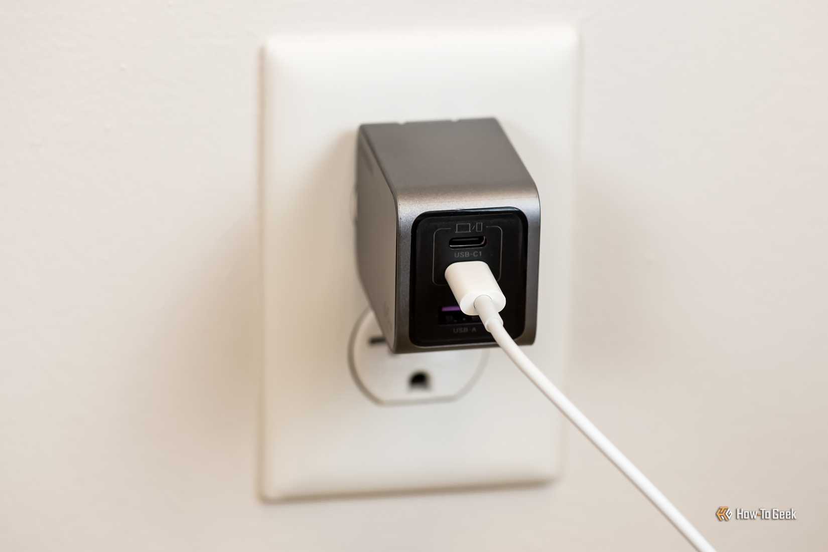 The Ugreen Nexode Pro 65W USB-C wall charger plugged into a wall outlet