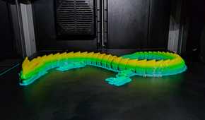 An image of a multi-colored 3D-printed dragon just after completion by the Creality K1 Max