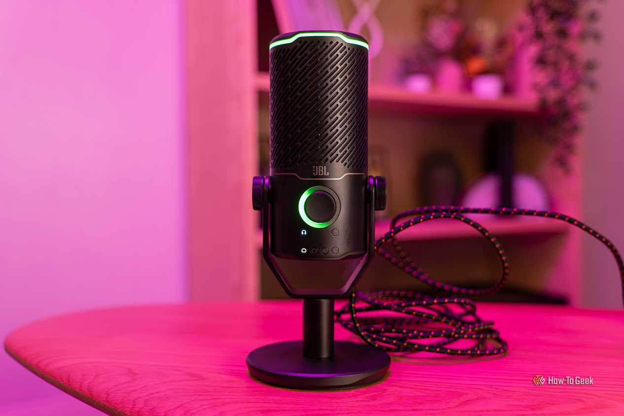 Микрофон JBL Quantum Stream Studio Включенный USB-микрофон JBL Quantum Stream Studio со светящимся индикатором на столе