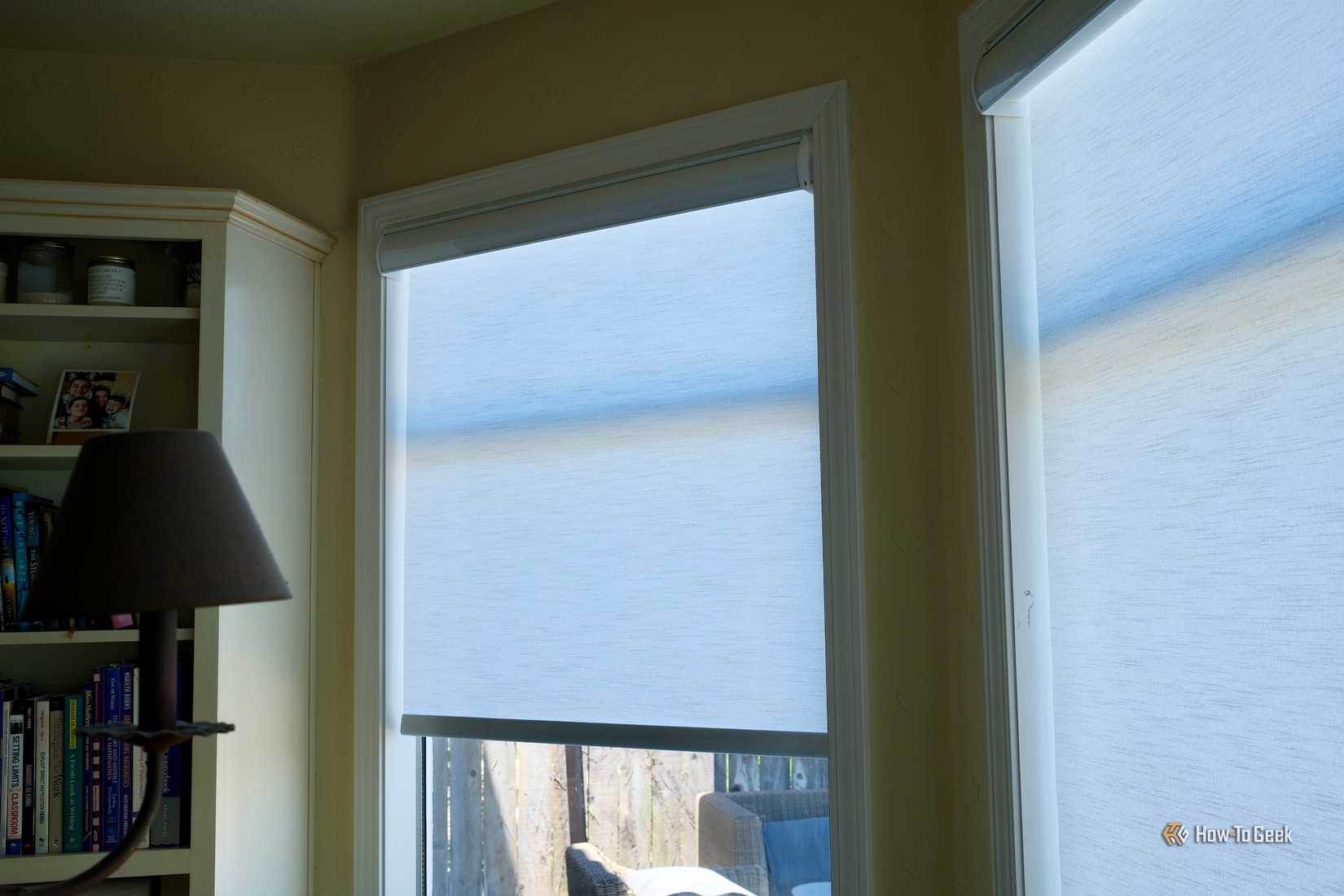 BlindsMagic Smart Motorized Roller Shades halfway closed on a window.