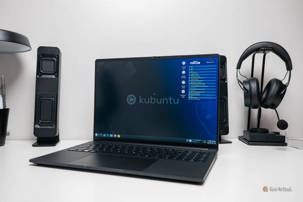 Kubuntu Focus Ir16 Gen 2 laptop on a desk with speakers and a headset in the background.