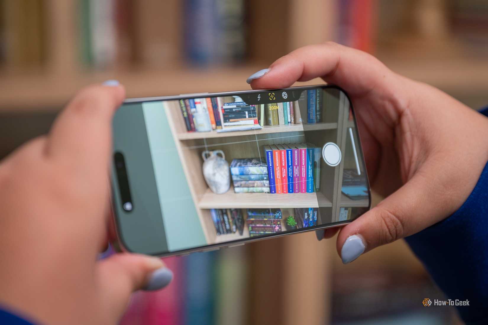 Pessoa tirando uma foto com o botão de controle da câmera do Apple iPhone 16 Pro em paisagem.