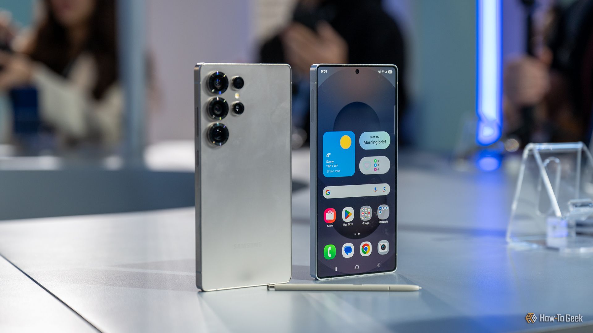 Samsung Galaxy S25 Ultra এর সামনে এবং পিছনে S Pen এর পাশে একটি টেবিলের উপর দাঁড়িয়ে আছে।