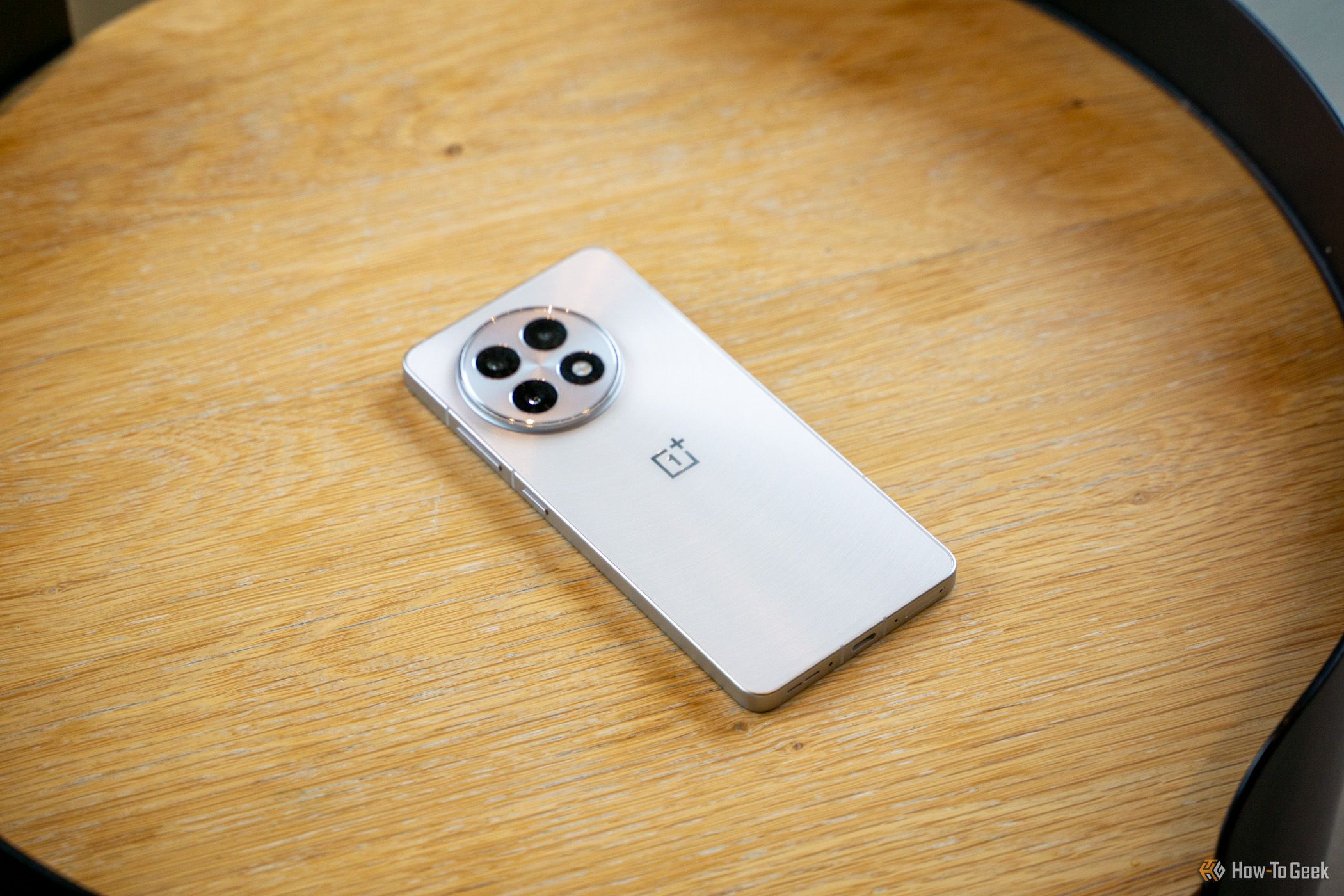 The OnePlus 13R sitting screen down on a wooden table showing the camera array.