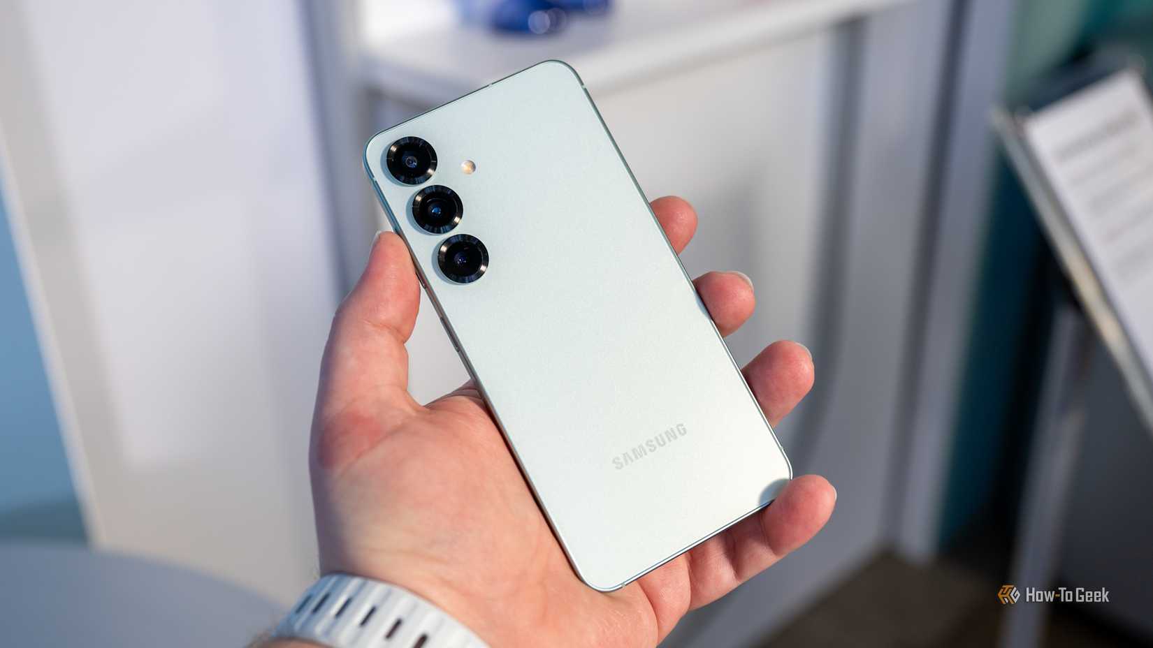 Person holding the Samsung Galaxy S25 looking at the rear cameras.